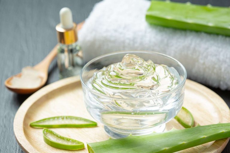 Aloe vera gel in a glass bowl with fresh aloe leaves.