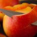 Knife peeling red apple skin smoothly.