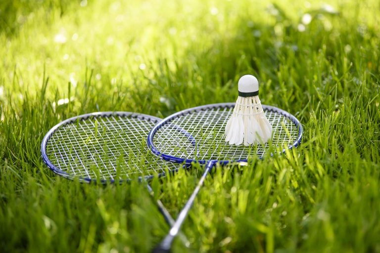 Badminton rackets and shuttlecock resting on grass.