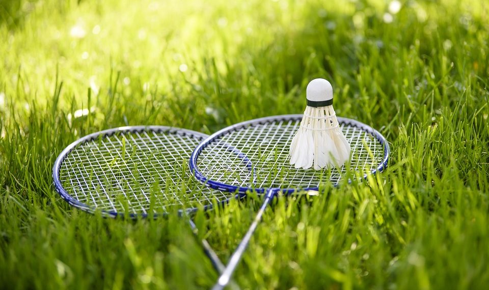 Badminton rackets and shuttlecock resting on grass.