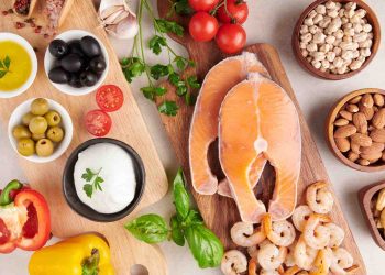 Salmon fillets with shrimp, vegetables, olives, and almonds on wooden boards.