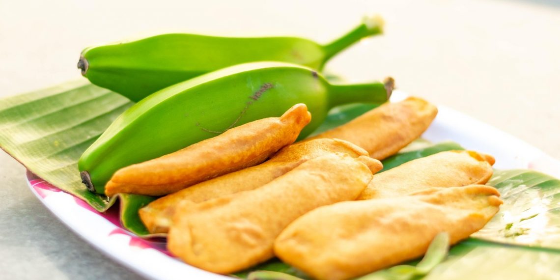 Fried bananas served on banana leaves with fresh bananas.