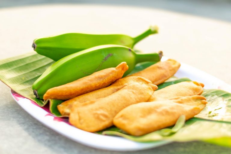 Fried bananas served on banana leaves with fresh bananas.