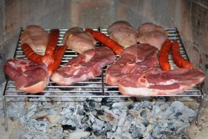 Grilling assorted meats over hot coals.