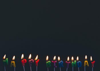 Happy birthday candles glowing against a dark background