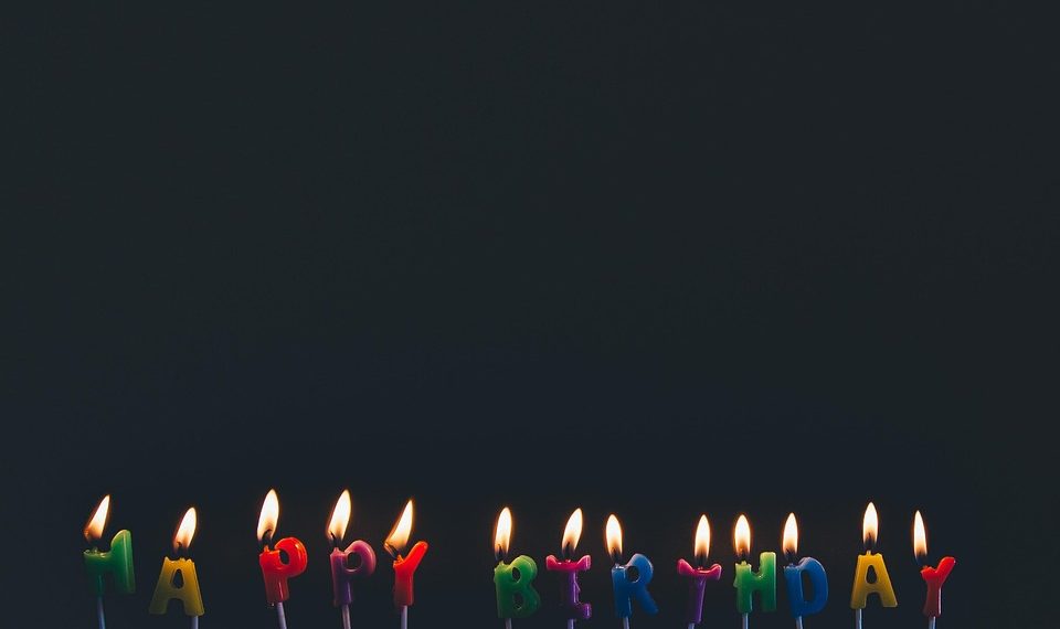 Happy birthday candles glowing against a dark background