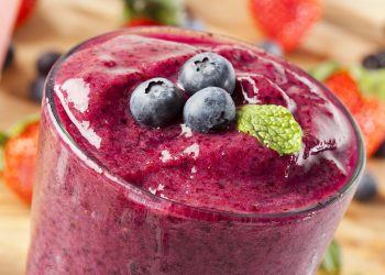 Blueberry smoothie topped with fresh blueberries and mint.