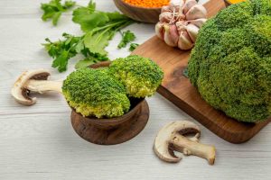 Broccoli and garlic with parsley and mushrooms on a wooden table.