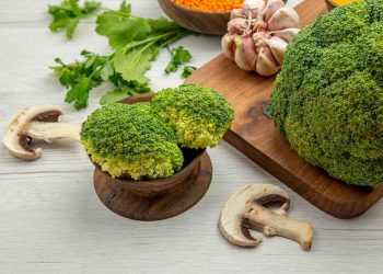 Broccoli and garlic with parsley and mushrooms on a wooden table.