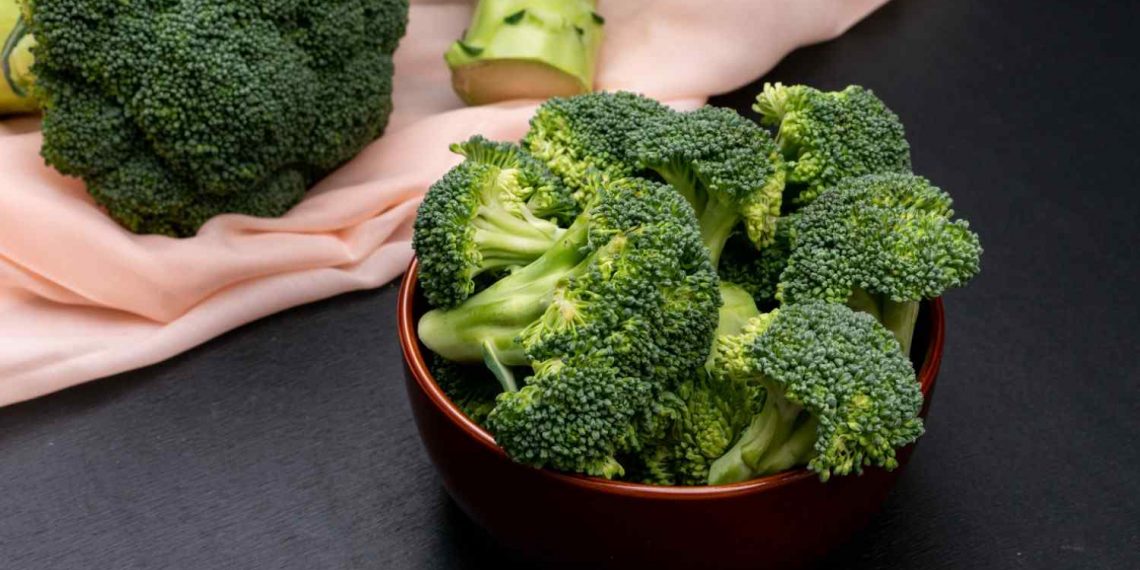 Bowl of fresh broccoli on a black table.