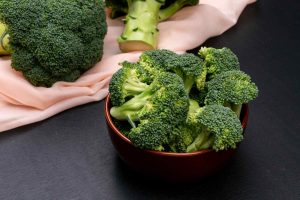 Bowl of fresh broccoli on a black table.