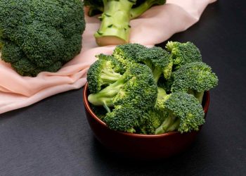 Bowl of fresh broccoli on a black table.
