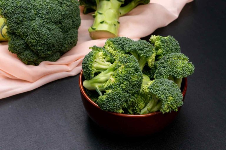 Bowl of fresh broccoli on a black table.