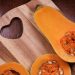 Half butternut squash on a wooden cutting board with heart design.