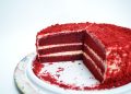 Red velvet cake with cream cheese layers on a white plate.