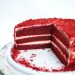 Red velvet cake with cream cheese layers on a white plate.
