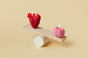 Heart and brain candles balancing on a wooden plank.
