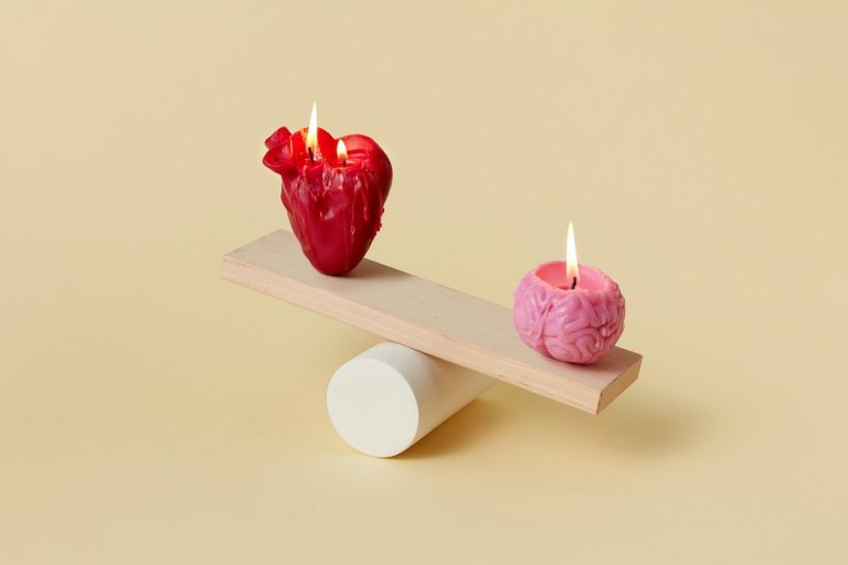 Heart and brain candles balancing on a wooden plank.