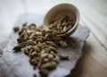 Cardamom pods spilling from a bowl on a stone tray.