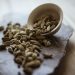 Cardamom pods spilling from a bowl on a stone tray.