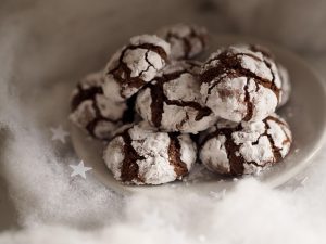 Chocolate crinkle cookies dusted with powdered sugar on a plate.
