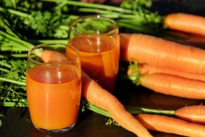 Carrot juice in glasses with fresh carrots on a table.