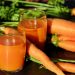 Carrot juice in glasses with fresh carrots on a table.