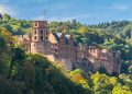Heidelberg Castle nestled in lush forest, viewed from afar.