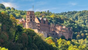 Heidelberg Castle nestled in lush forest, viewed from afar.