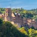 Heidelberg Castle nestled in lush forest, viewed from afar.
