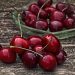 Juicy red cherries in a glass bowl on wooden table.