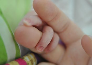 Adult holding a baby's hand gently.