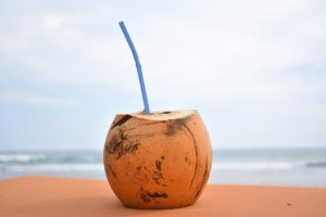 Coconut with a straw on a sandy beach background.