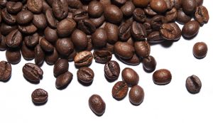 Roasted coffee beans scattered on white background.