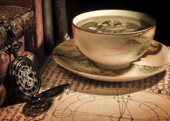 Antique teacup and pocket watch on parchment.