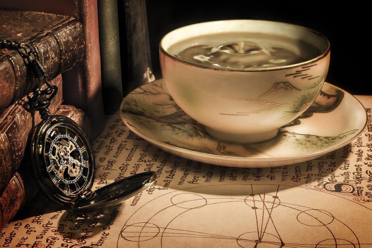 Antique teacup and pocket watch on parchment.