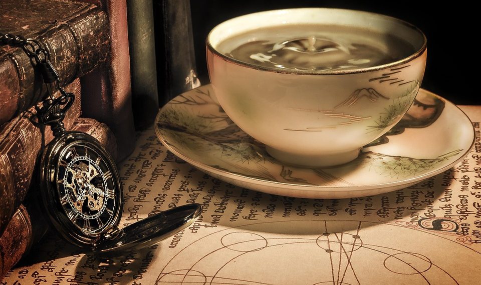 Antique teacup and pocket watch on parchment.