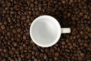 Empty coffee cup on scattered coffee beans.