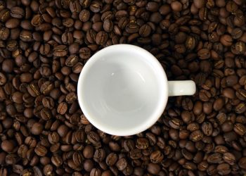 Empty coffee cup on scattered coffee beans.