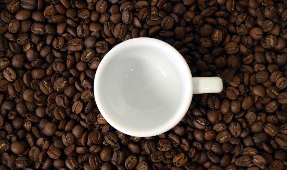 Empty coffee cup on scattered coffee beans.