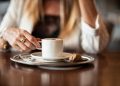 Woman enjoying a cappuccino at a cafe table.