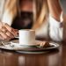 Woman enjoying a cappuccino at a cafe table.