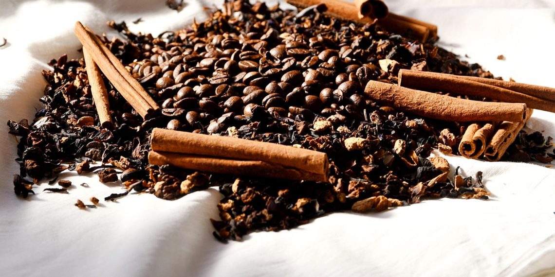 Cinnamon sticks and coffee beans arranged on cloth