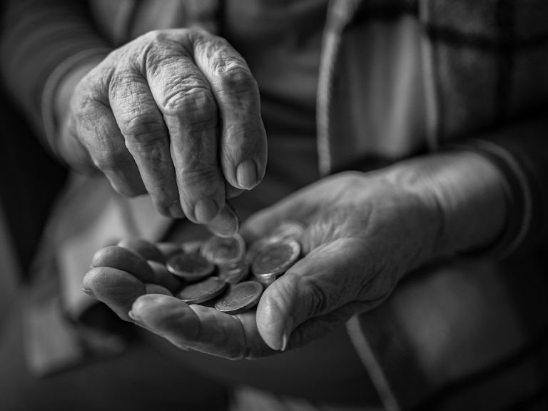 Elderly person counting coins in their hands.
