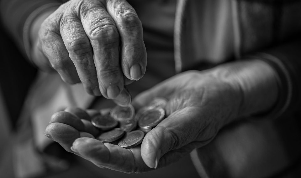 Elderly person counting coins in their hands.