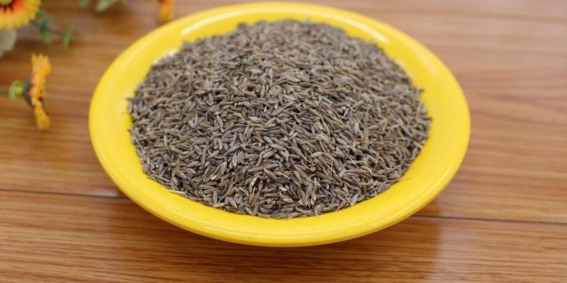 Cumin seeds on yellow plate, ideal for flavorful cooking.