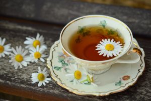 Tea cup with chamomile flowers on wooden table.