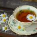 Tea cup with chamomile flowers on wooden table.