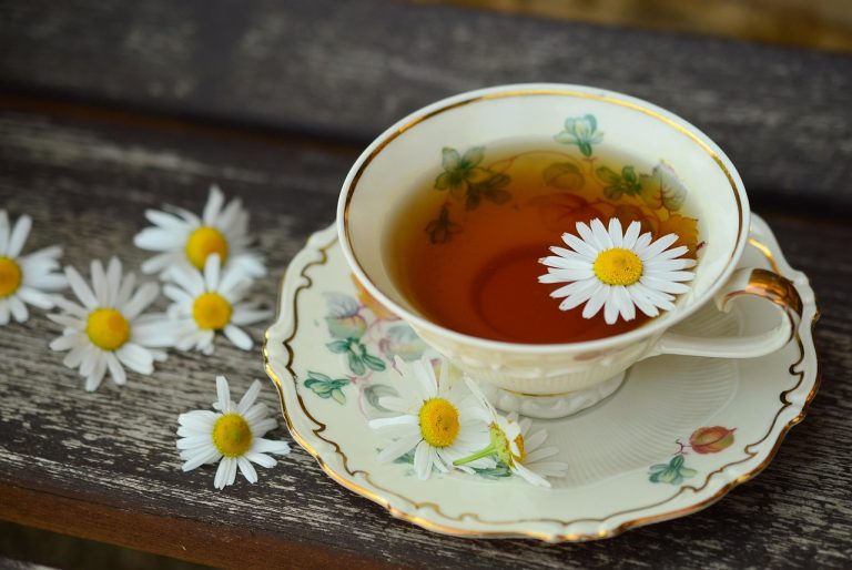 Tea cup with chamomile flowers on wooden table.