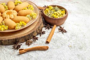 Plate of cookies with flowers, star anise, and cinnamon sticks on rustic surface.